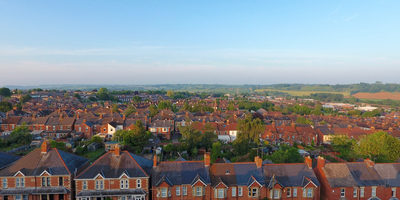 An aerial photo of brick houses in the UK with blue skies and country side