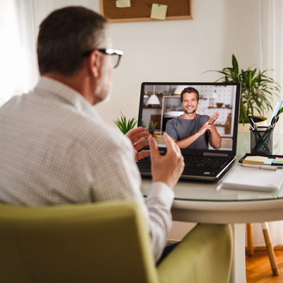 A man sat at home conducting sign language on a video call on the laptop