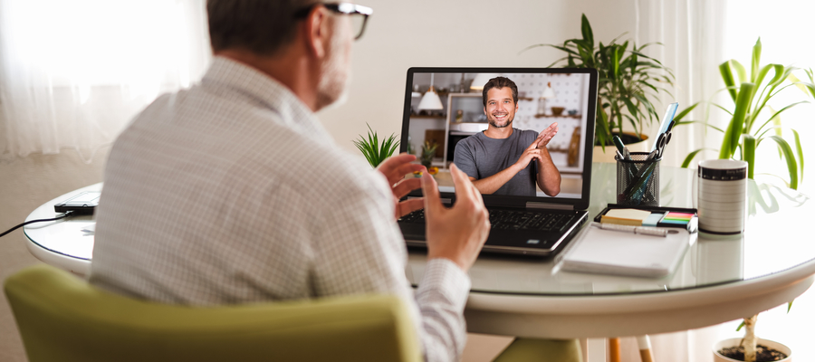 A man sat at home conducting sign language on a video call on the laptop