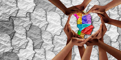 A group of hands creating a heart shape around a multicoloured face