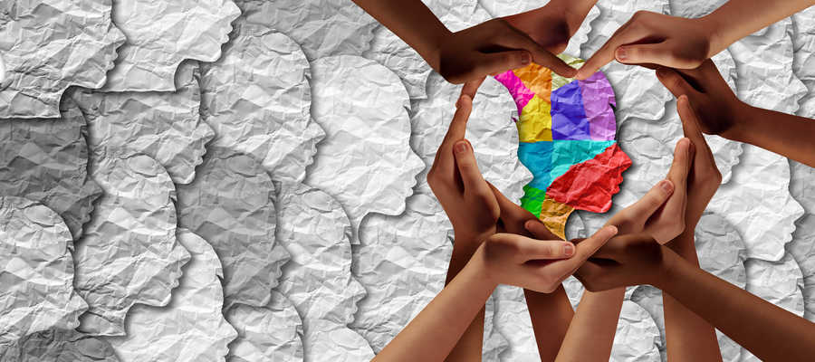 A group of hands creating a heart shape around a multicoloured face